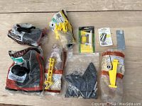 Various bags containing plastic cap nails, hinges, and gate pulls arranged on a wood surface.
