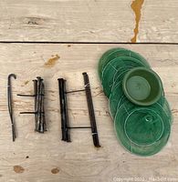 Photo of metal curtain rod pieces, mounting brackets, curtain hooks, and green plastic saucers for drying rack