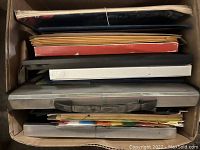 Box with file folders and binders in various colors including red, black, blue, white, and yellow.