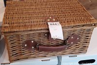 Front view of closed wicker picnic basket with leather handle and metal hardware for secure closure.