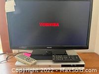 Toshiba 24 inch flat screen TV powered on with Toshiba logo on screen, DVD player with two remotes on top.
