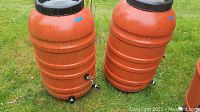 Two orange barrels on grass showing paired condition and fittings