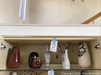 Front view of six Asian decor items: 5 vases with differing shapes and patterns and one traditional Daruma figure