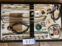 Full overview of the jewelry lot on display board including necklaces, bracelets, pins, and earrings arranged for viewing