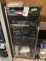 Full view of Fisher stereo components housed in wooden cabinet with glass door