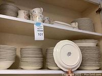 Three shelves of plates, bowls and cups with Noritake stamp on bottom plate
