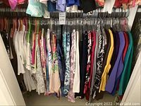 Photo showing rack of ladies blouses in various colors and patterns on hangers