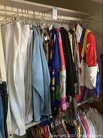 Overview of hanging white pants, denim shirt, animal print blazer, black and purple blazers, and windbreakers