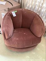 Front view of one brown velvet swivel barrel chair showing seat cushion and curved backrest.