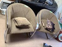 Pair of beige corduroy upholstered barrel chairs with tubular chrome frames, front view