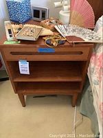 Front view of one nightstand showing top drawer and open shelving with belongings on top