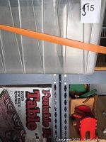 Portable folding table folded and strapped showing plastic top and metal legs