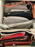 Top view showing multiple purses layered together highlighting different textures and colors including beige woven and black leather purses