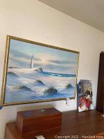 Large framed lighthouse and beach landscape painting, signed by K. Wilson, above wooden chest