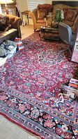 Full view of the Mahal carpet placed in living room with red dominating floral pattern and black borders.