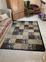 Manhattan Ottomanson area rug laid on floor next to sofa and chairs, showing full pattern and color scheme.