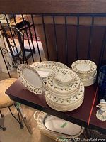 Overall view of Narumi China Encanto dinnerware set stacked with multiple plates, saucers, bowls, and platters.