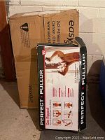 Boxes of Perfect Pull-Up and Easy Shaper fitness machines stacked together in a basement area.