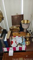 View of entire lot showing Bibles, crucifix, metal chalices, metal tray and wooden box with inscription.