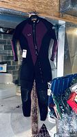Front view of Seaquest wetsuit hanging in basement showing purple panels and front zipper.
