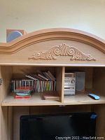 Sony micro HiFi stereo system with cassette and CD player inside wooden cabinet, visible collection of CDs and remote control next to the unit.