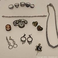 Photo showing five sterling silver rings, a bracelet with stones, cameo brooch pendant, telephone brooch, hearts earrings, dangling earrings, rope chain necklace, and abalone turtle pendant.