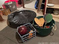 Photo showing trampoline, basket with bowling ball and weights, and basket with paddleball equipment
