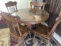 Round wooden kitchen table with glass top and 4 matching solid wood chairs with carved backs