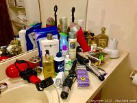 Photo of various toiletry items on bathroom counter including hair dryer, hair care products and grooming kit