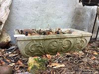 Single planter side view showing raised scroll and floral relief pattern on long side.