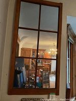 Photo of the antique pine window frame showing six glass panes with wooden muntins dividing the panes, reflecting an interior room with furniture.