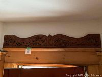 Entire carved fretwork panel mounted above wood door frame, item tag visible
