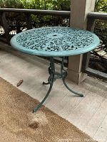 Side view of green cast metal round patio table on porch