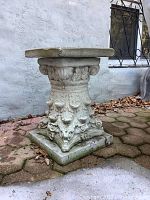Front angle view of the cement garden pedestal showing ornate carvings and weathered surface.