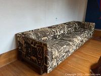 Three-quarter view of left side showing full sofa length, fabric pattern and teak leg