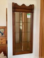 Full view of the long narrow mirror mounted on a wall showing the wooden oak frame and width relative to doors and furniture nearby.