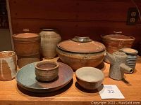 Front view of lot showing all nine pottery pieces on wooden surface