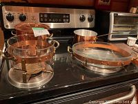 Large French copper stockpot with lid and small copper saucepan on cooktop