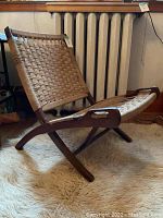 Side profile view showing curved wooden frame, folding mechanism, and woven seat/back