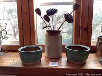 Pair of pottery planters placed on a wooden window sill showing both planters and a white ceramic vase in the background.