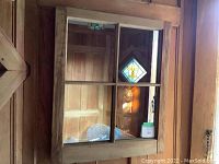 Full view of the 4 pane pine mirror hanging on a wooden wall, showing its size, frame and divided glass panes.