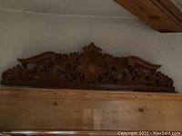 Close-up of ornate central medallion and scroll motifs on carved wooden trim