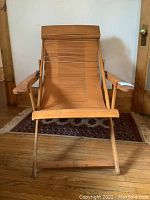 Front view of unfolded bamboo lounge chair showing slatted seat and removable headrest cushion.