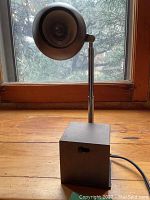 Front view of single lamp showing cube base, telescoping arm, and shade