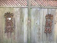 Overall view of two wrought iron decorative acorn plaques mounted on fence