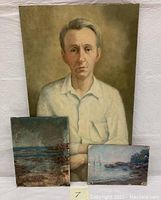 View of three oil paintings on board including gentleman portrait and two seascapes stacked against a wall.