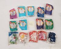 Fifteen TY Beanie Babies McDonald's Happy Meal toys in original sealed plastic bags with numbered inserts visible, arranged in two rows.