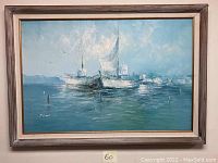 Full view of the framed nautical oil painting showing two sailing ships on water with distant land and cloudy sky.