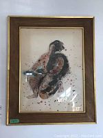 Front view of framed art print depicting a stylized figure holding fish, framed in a wooden frame with gold trim, showing paper discoloration and minor stains