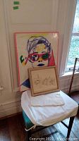 Overall view of two artworks leaning on stool